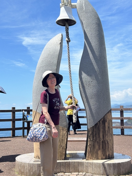 Japan 2024---05-04-07_My wife hitting the bell of XYZ Bell Tower near Sea of Cross.jpg