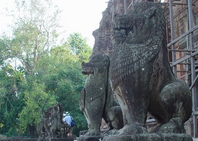 Cambodia 2006 --- Day 04-06 Preah Ko --- 02 There are a row of stone lions in front of several tower ruins.JPG